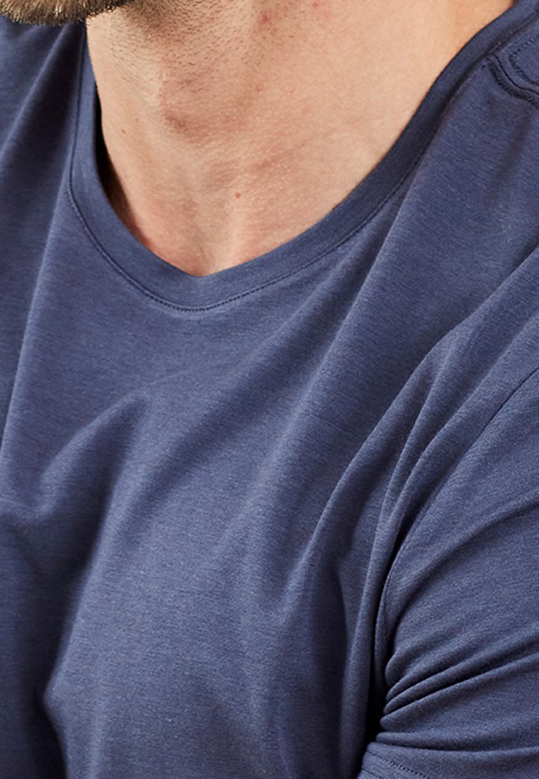 Mørkeblå kortærmet T-shirt med rund halsudskæring og glat, let stof med en subtil struktur og drapering.