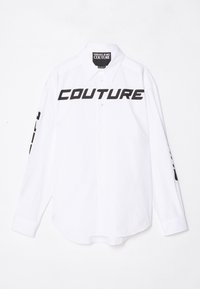 Weißes Langarmshirt aus Baumwolle mit schwarzem "COUTURE"-Aufdruck auf der Vorderseite und Text auf den Ärmeln. Knopfverschluß und abgerundeter Saum.