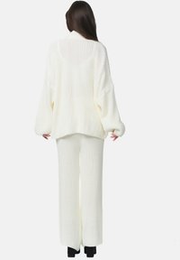 Ensemble en tricot blanc en deux pièces, comprenant un pull ample avec des épaules tombantes et un pantalon large en texture côtelée.