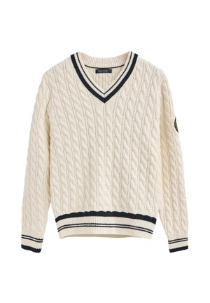 Jersey de punto trenzado en color crema con escote en V y puños y dobladillo de rayas navy acanaladas. Incluye una insignia en la manga izquierda.