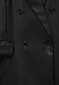Manteau en cuir noir à double boutonnage avec quatre boutons noirs et une poche à rabat sur le côté gauche.
