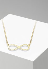 Collana in oro con pendente a forma di infinito dal superficie liscia e lucidata. Design semplice con catena a maglia delicata.