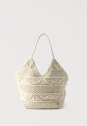 Geantă tote macramé de culoare crem cu modele țesute intricate și o singură mâner buclă pe un fundal simplu.