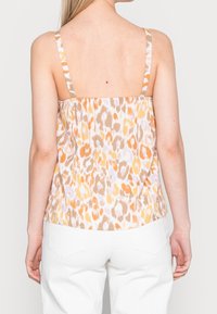 Top sin mangas con un patrón de leopardo en tonos naranja, beige y blanco. Presenta tirantes finos y un ajuste relajado. Vista trasera mostrada.