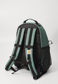 Rucsac cu un design din țesătură verde și neagră, având curele căptușite, buzunare laterale din plasă și un sistem de cataramă ajustabil.