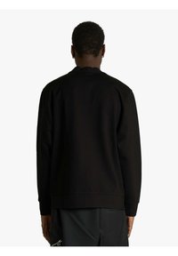 Felpa nera con scollo a girocollo, polsini a costine e finitura testurizzata. Design semplice, senza loghi o motivi visibili. Vista posteriore mostrata.