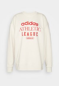 Roomkleurige sweatshirt met een ronde halslijn, doorgezakte schouders en rode grafische tekst: "adidas ATHLETIC LEAGUE" aan de voorkant.