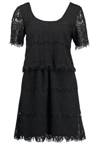 Svart spetsklänning med en figurnära överdel som har korta ärmar och rundad halsringning. Betonar med en scalloped nederkant och fransade kanter.