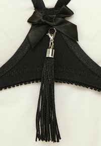 Crni bralet s naglaskom na mašnu, srebrnim kopčanjem i detaljima od crnih resica. Glatka tekstura tkanine s dekorativnim šavovima na rubovima.