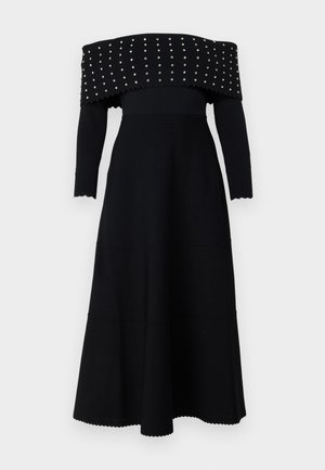 Black off-the-shoulder dress with long sleeves, ribbed texture, scalloped edges, and silver studs along the neckline and bodice.