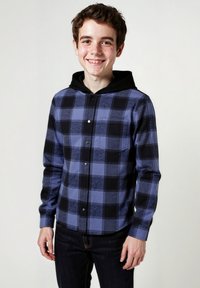 Camicia a maniche lunghe a quadri blu e nera, con chiusura a bottoni sul davanti, taschino sul petto e cappuccio nero a contrasto. Tessuto morbido.