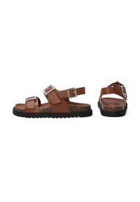 Braune Ledersandalen mit zwei verstellbaren Riemen, silberfarbenen Schnallen und einer strukturierten Korksohle auf einer schwarzen Gummisohle.