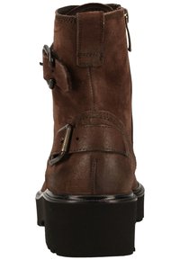 Brown suede ankle boot with a rounded toe, side zip closure, decorative strap and buckle detail, and thick black sole.