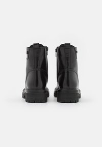 Botas de tobillo de cuero negro con un acabado suave, talón reforzado y cremalleras laterales. Suela de goma texturizada y resistente para un agarre mejorado.