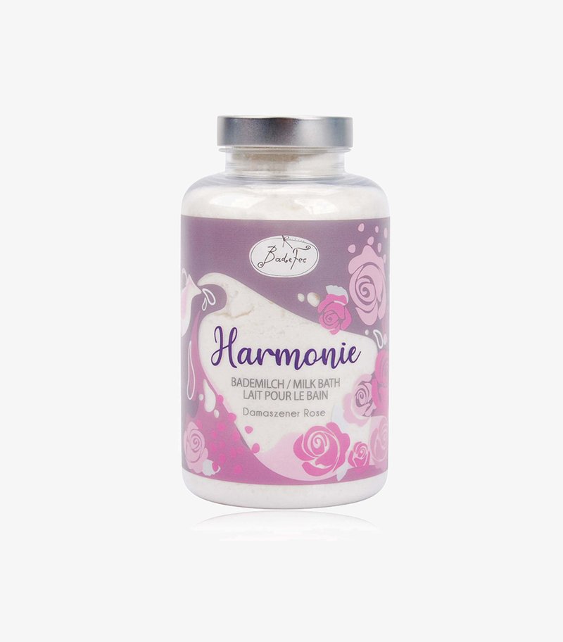 Clear glass jar with a silver lid containing white milk bath powder. Label features lavender and pink floral designs, reads "Harmonie."