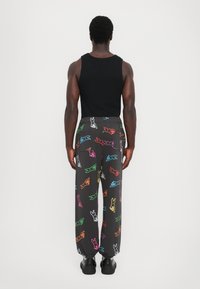 Zwart stoffen sweatpants met een losse fit, versierd met kleurrijke cartoonkonijnenprints. Afgewerkt met een elastische tailleband en boorden.