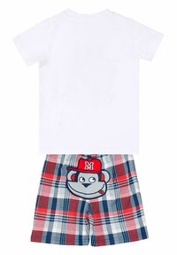 Hvid bomulds T-shirt, parret med ternede shorts med røde, blå og grå mønstre og et broderet abe-design med en rød kasket.