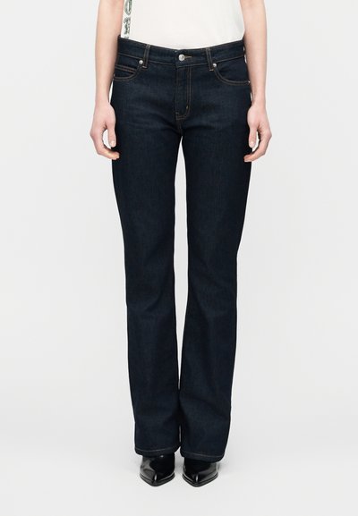 Jean en denim bleu foncé avec une coupe droite, style cinq poches, coutures en cuivre et une fermeture à bouton unique à la taille.
