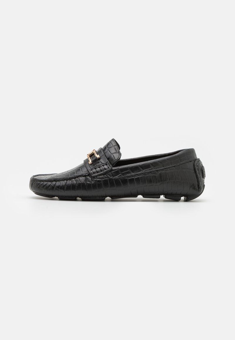 Black crocodile-patterned leather loafers with a round toe, featuring a gold buckle accent and textured sole for grip.