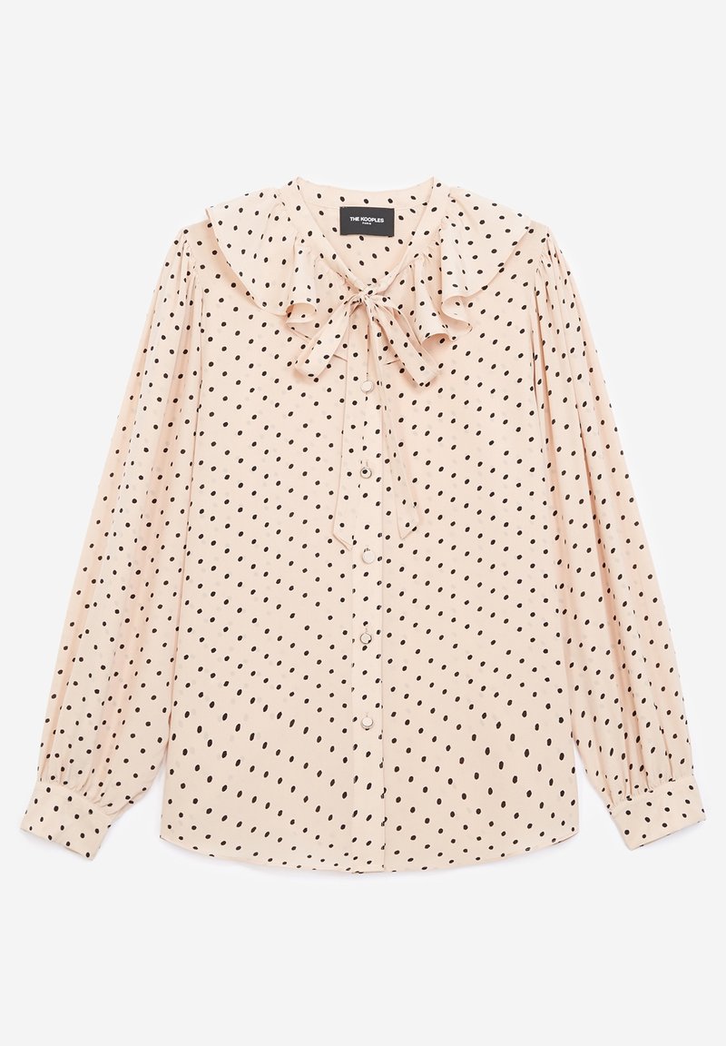 Blouse rose clair à manches longues avec pois noirs, col volanté, boutons devant et un nœud noué au niveau de l'encolure.