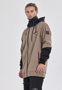 Beige und schwarze Windbreaker-Jacke mit Reißverschluss, Kapuze, mit Reißverschluss versehenen Taschen und Logo-Details. Sie hat eine lockere Passform und einen strukturierten Stoff.
