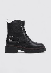Bottine en cuir noir avec finition texturée, lacets à l'avant, détail de boucle sur le côté, semelle en caoutchouc épaisse et coutures contrastées.