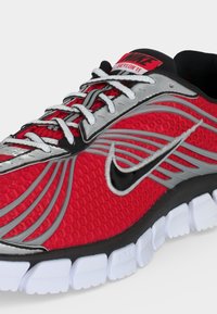 Κόκκινο και ασημί παπούτσι για τρέξιμο Nike Skylon 11 με μαύρο λογότυπο Swoosh και λευκή τμηματοποιημένη σόλα, από μπροστινή πλευρά.