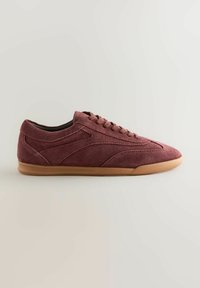 Suede maroon sneaker with a low profile, round toe, flat lace-up design, and a tan rubber sole. Features subtle side stitching accents.