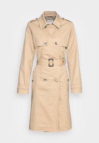 Cappotto beige con design doppiopetto, bottoni argentati, vita con cintura e maniche lunghe. Presenta tasche laterali e un colletto.