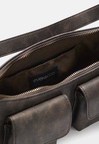 Ciemnobrązowa skórzana torba na ramię z złotym zamkiem błyskawicznym, dwiema przednimi kieszeniami i materiałowym wnętrzem oznaczonym "even&odd."
