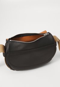 Borsa a tracolla in pelle nera con superficie testurizzata, chiusura con zip e interno beige. Presenta una tracolla in tessuto beige per una vestibilità regolabile.