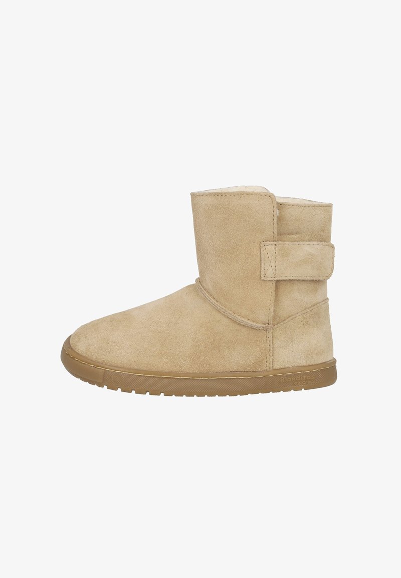 Botín de ante color marrón claro con un forro interior suave, suela plana de goma y cierre con correa lateral. Textura lisa con detalles mínimos de costuras.