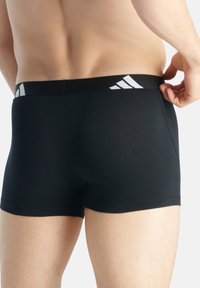 Svarta bomullboxer med en åtsittande design, elastisk midjeband med tre vita ränder och slät textur.