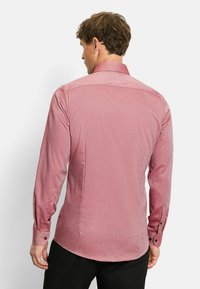 Red patterned long-sleeve shirt with a fitted design, a pointed collar, and buttoned cuffs. Back features subtle seam detailing and curvature.