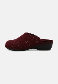 Zoccoli in feltro bordeaux con bordo scallopato, punteggiati da piccoli dettagli metallici, e una suola bassa nera a zeppa. Texture liscia e forma arrotondata.