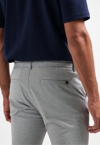 Grijze stretchbroek met een slim fit, voorzien van een platte voorkant, achterzakken en een klein logoaccent. Zachte stof met een gladde textuur.