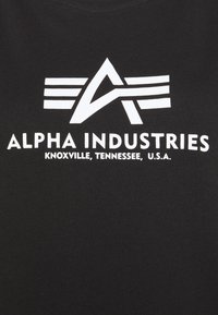 Svart bomull T-skjorte med et hvitt grafisk design som har bokstavene "A" og "I", samt teksten "ALPHA INDUSTRIES, KNOXVILLE, TENNESSEE, U.S.A."