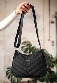 Černá prošívaná kabelka s vzorem do šikmého pruhu, má zipové zapínání a nastavitelné ramenní popruhy, vyrobená z hladkého materiálu s lesklým povrchem.