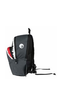 Gray shark-themed backpack with a mesh side pocket, large white teeth, and a round eye design. Features adjustable straps and zippers.