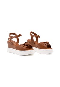 Sandali wedges in finta pelle marrone con dettaglio annodato nella parte anteriore, cinturino alla caviglia regolabile e suola piatta bianca con lettering del marchio.