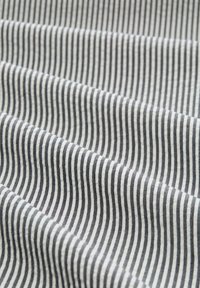 Tissu rayé avec des lignes alternées de fins traits blancs et gris foncé, avec une texture douce, disposé en plis légers.