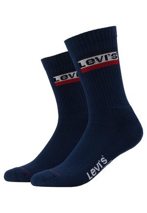 Marinblå strumpor med ribbad textur, med ett vitt och rött randigt logoband och vit varumärkestext på sulan.