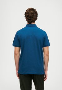 Dark blue polo shirt with short sleeves and a collar. Features a smooth texture and a straight cut design at the hem. No visible branding.