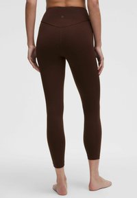 Bruine high-waisted leggings van rekbaar materiaal, met een naadloos ontwerp en een aansluitende silhouette, die net boven de enkels eindigen.
