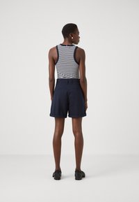 Top senza maniche a righe con pantaloni corti blu navy; il top ha un bordo blu navy, i pantaloni sono lunghi fino al ginocchio con risvolti e una texture liscia.