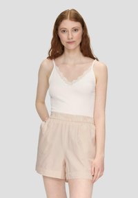 Weißes geripptes Tanktop mit Spitzensaum, kombiniert mit hellbeigen gestreiften Shorts mit elastischem Bund und seitlichen Taschen.