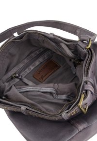 Grijze zachte leren handtas met een gevoerde binnenkant met vakken, messing hardware en een bruine leren logo-label. Inclusief ritsvakken.