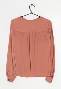 Blusa a maniche lunghe in rosa pallido con schiena plissettata, collo tondo e dettagli con bottoni ai polsini. Tessuto morbido e leggero con una texture liscia.
