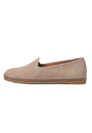 Beige suède instappers met een ronde neus en decoratieve stiksels langs de zool. Voorzien van een platte, geweven espadrille-achtige basis.