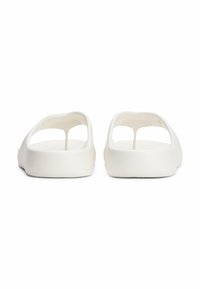 Sandalias de plástico blancas con apertura en la parte trasera y agarre para los dedos. Presentan detalles troquelados para transpirabilidad y una textura suave y mate.